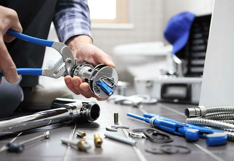 Technician repairing a plumbing fixture with professional tools in Carlsbad