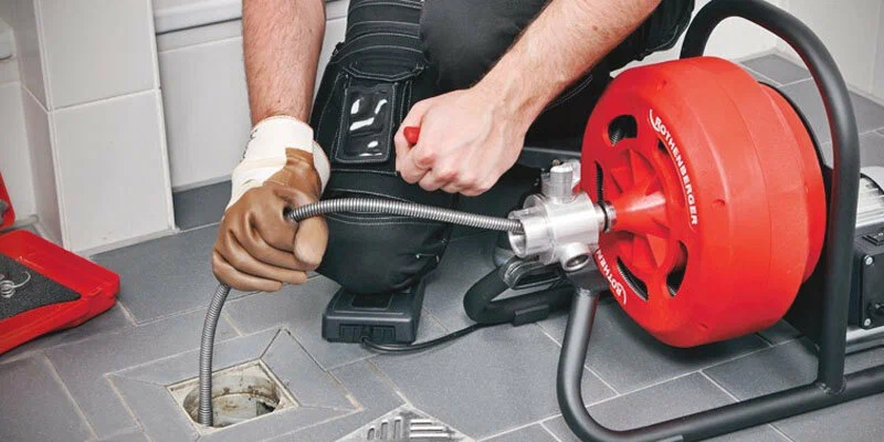 Plumber using a drain-cleaning machine in Carlsbad