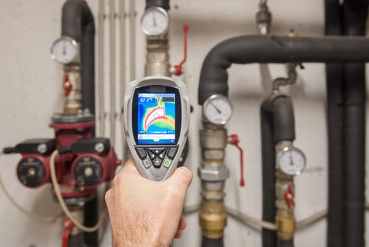 Plumber using a thermal imaging camera to inspect pipes in Carlsbad