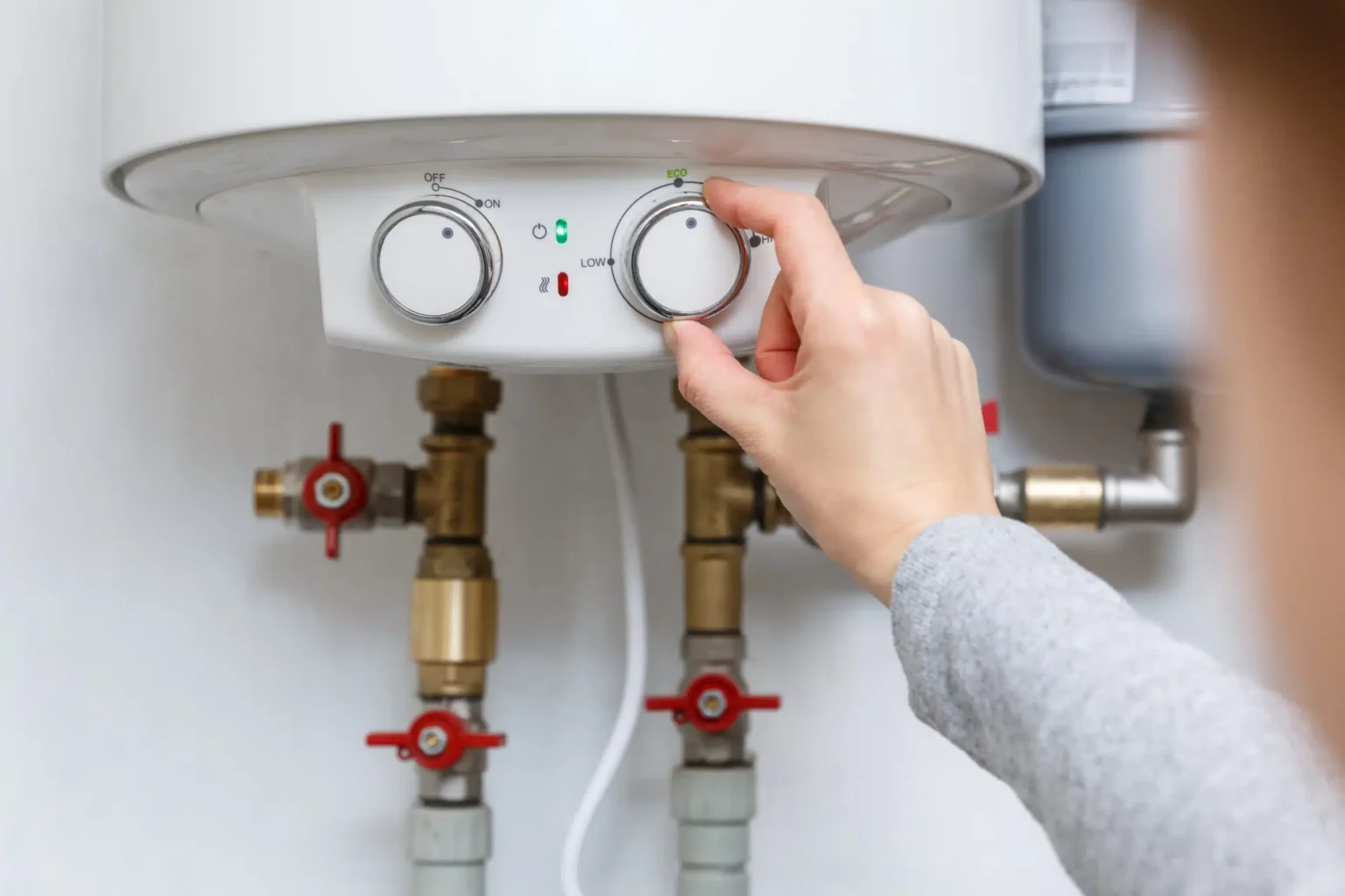 Homeowner adjusting the temperature controls on a water heater in Carlsbad